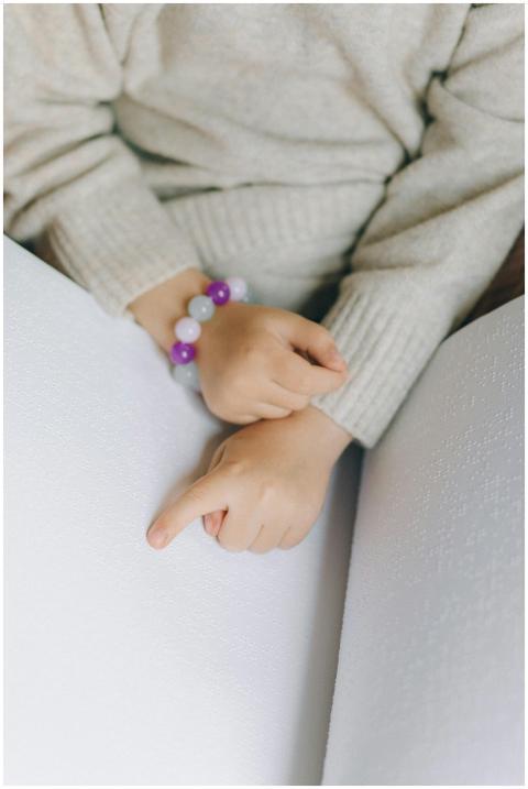 A child uses their fingers to read a book in brail