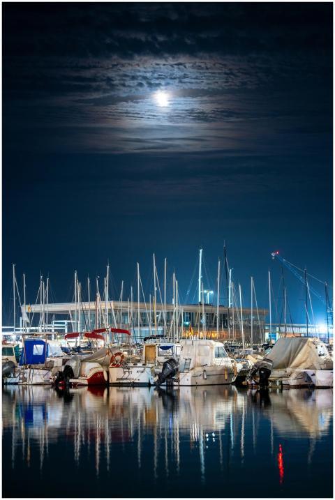 Moonlit view of sailboats and yachts reflecting in