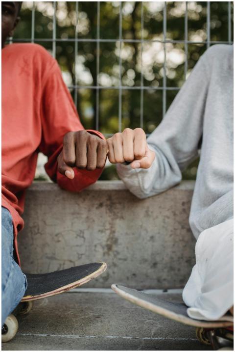 Two teenagers sharing a fist bump while sitting wi