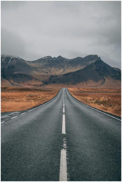 A scenic empty road stretches into snow-capped mou