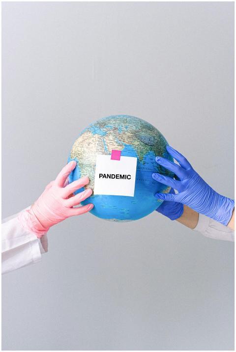 Gloved hands holding a globe with 'Pandemic' text,