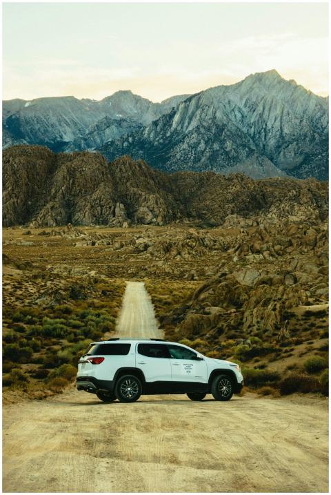 White SUV on a dirt road in a rocky mountainous la