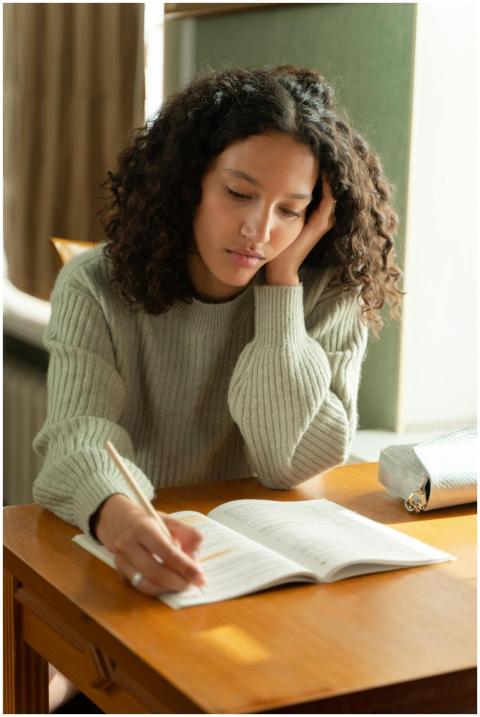 Teenage girl with curly hair studying at a desk, c