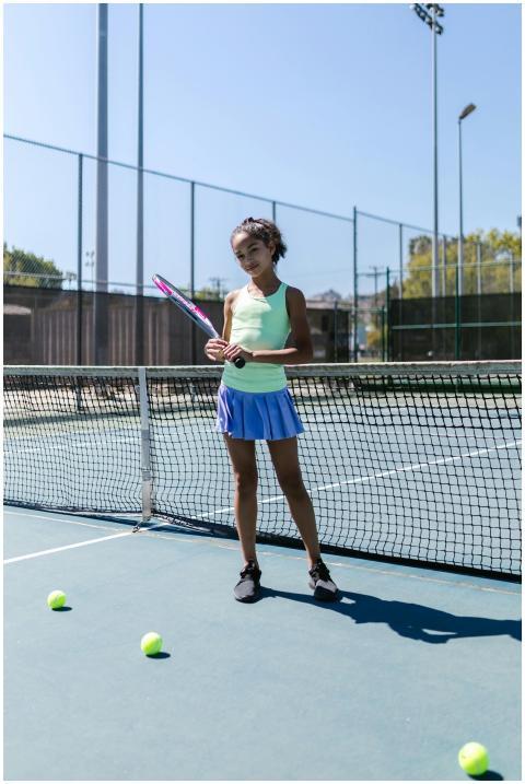 Teen girl holding tennis racket on court, surround