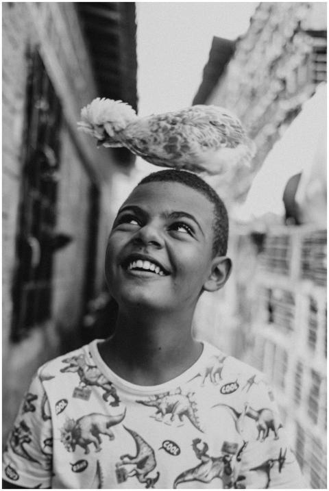 A joyful child with a chicken on his head, smiling