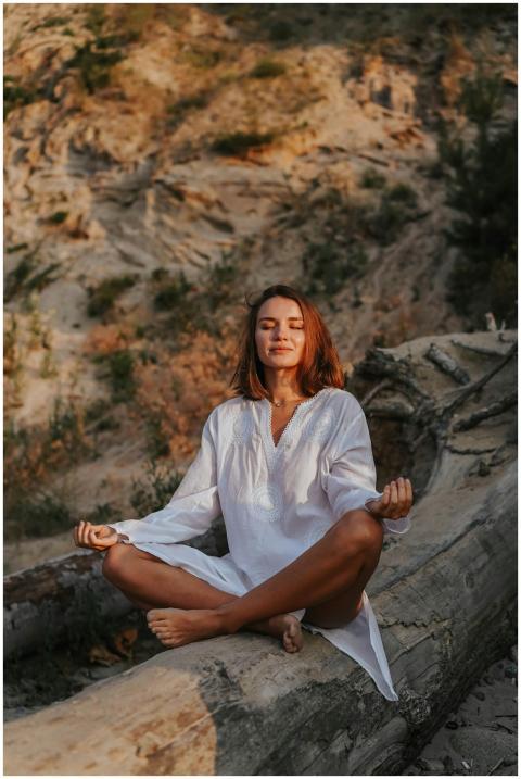 Woman in white dress meditating outdoors on a tree