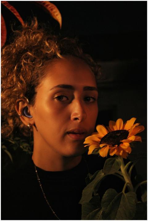 Close-up portrait of a woman with a sunflower, cap