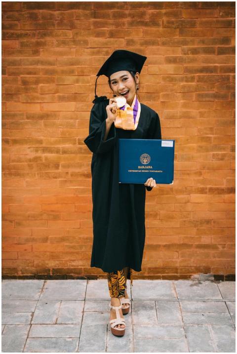 Joyful graduate in cap with diploma and medal agai