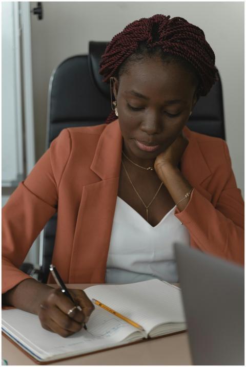 African American woman in a blazer writing in a no