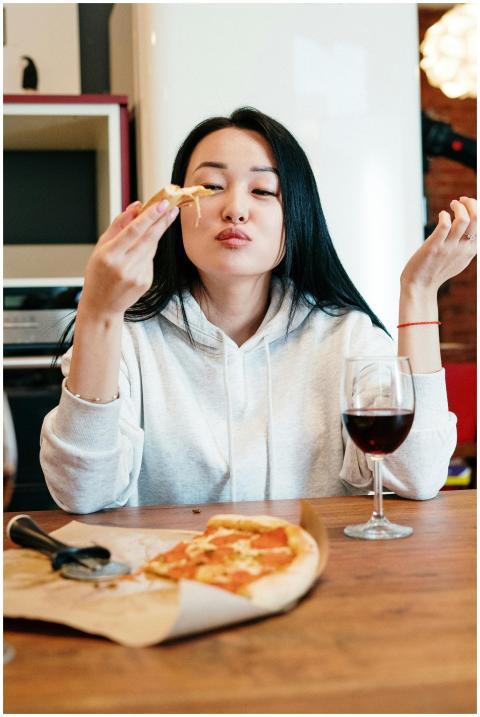 Woman savoring a pizza slice with a glass of wine