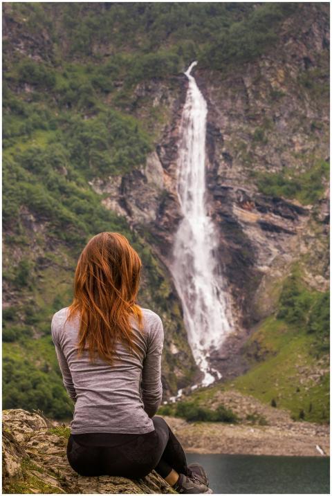 Young woman sits facing Cascade d'Ars waterfall in