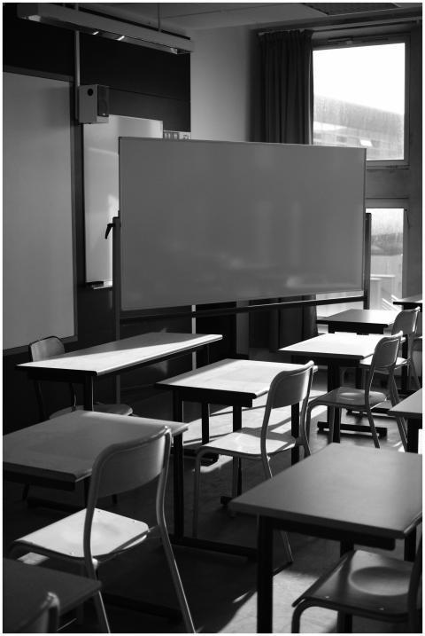 A black and white photo of an empty classroom with