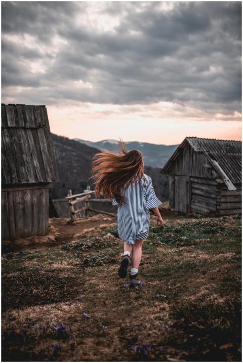 A young girl runs through a rustic countryside lan