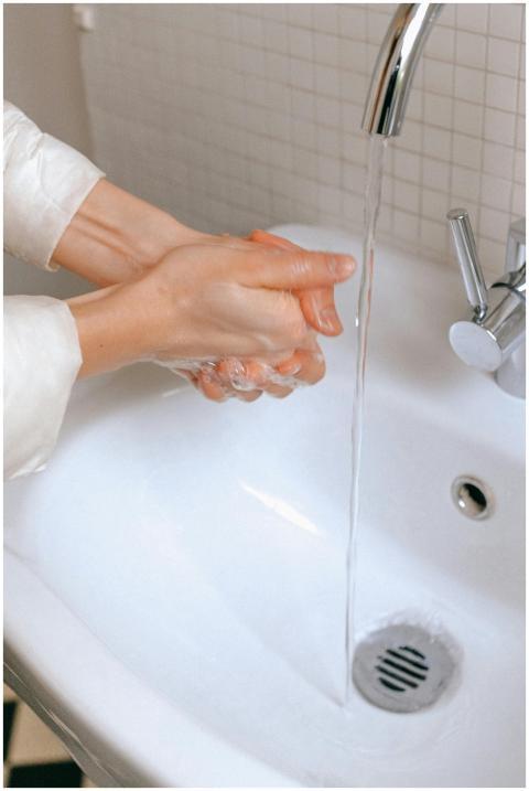 Close-up of hands being washed with water and soap