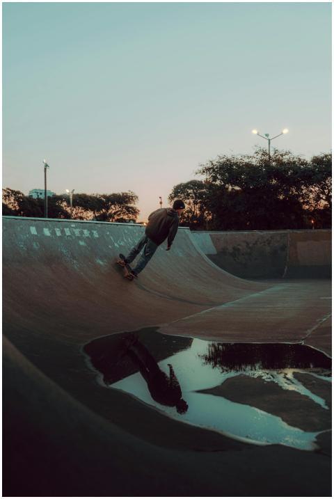 Male skateboarder rides ramp at a skate park durin