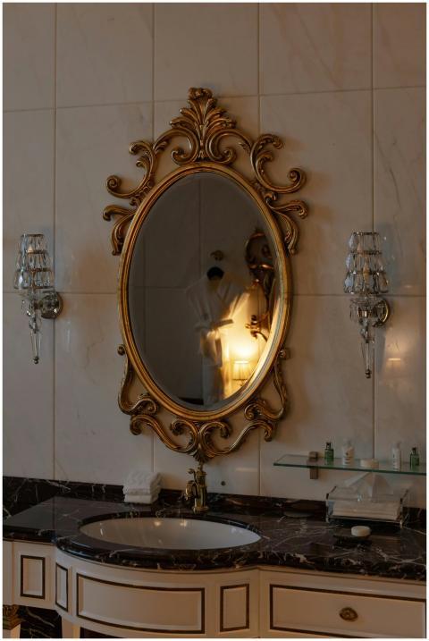 Luxurious bathroom with ornate oval mirror and cla