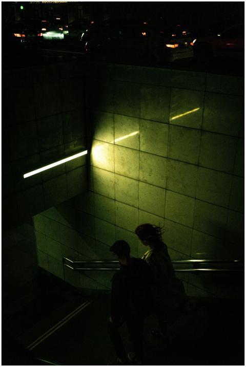 A couple descends into a dimly lit subway entrance