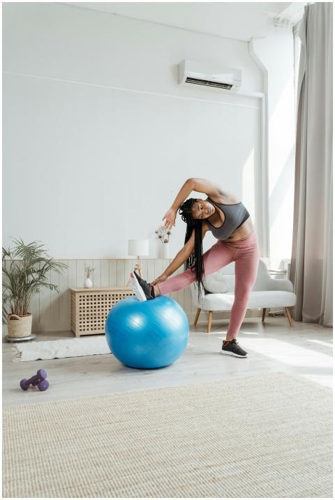 A woman in activewear stretches with a yoga ball i