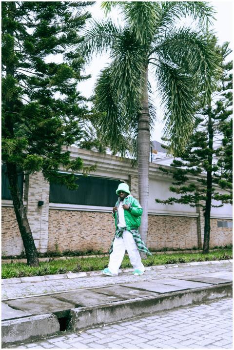 A stylish man in a green outfit walks confidently