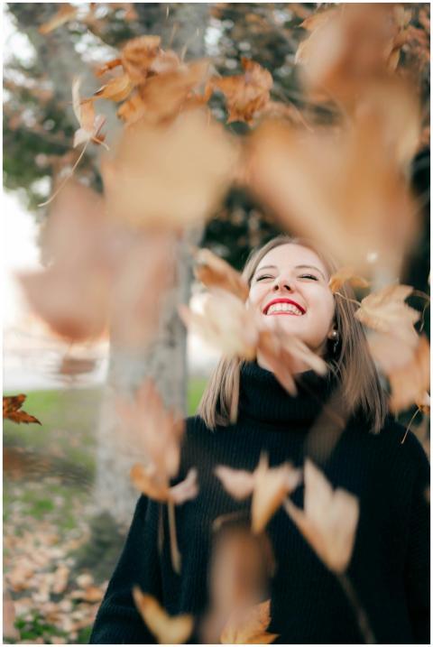 Joyful woman in autumn setting surrounded by falli