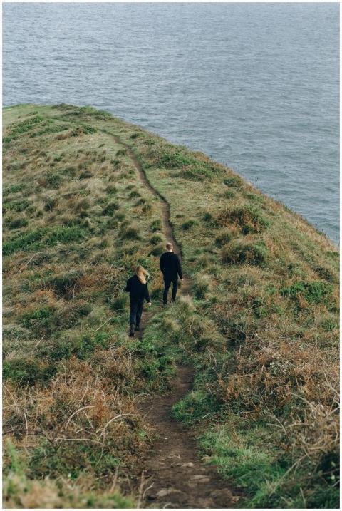 Two hikers walking on a scenic coastal cliff trail