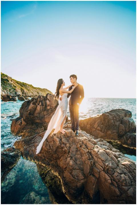 A couple posing on rocky seaside for a wedding pho