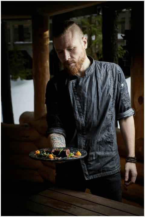 A chef showcasing a plated gourmet dish in a rusti