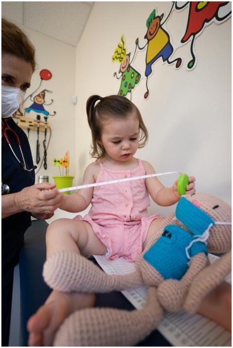 A pediatrician assists a toddler during a routine