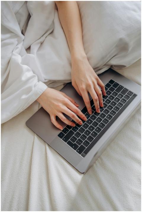 Hands typing on a laptop while resting on a comfor