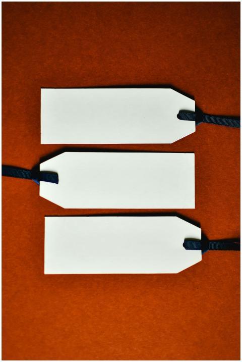 Three white tags with blue ribbons on an orange ba