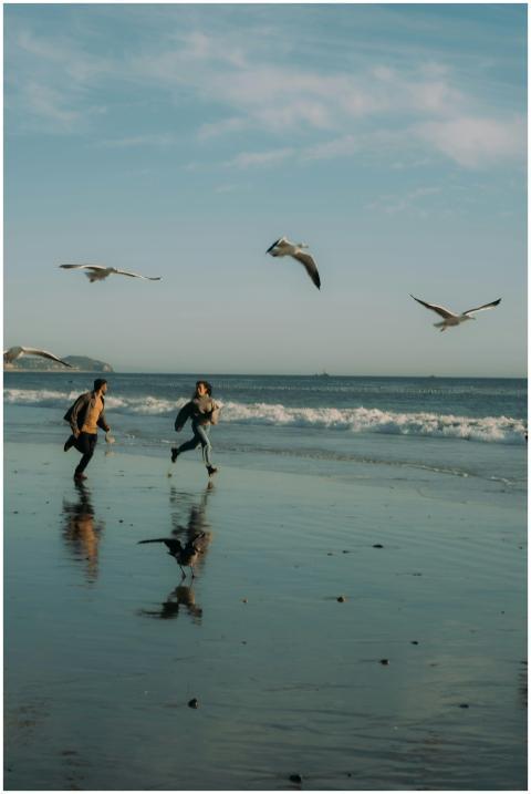 A joyful couple runs along a sunny Los Angeles bea