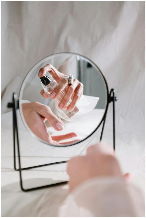 A graceful hand holding a perfume bottle reflected