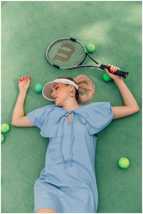 Elegant woman in blue dress poses with tennis rack