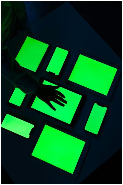 Hand reaching over various electronic devices with