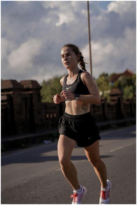 A female runner in athletic wear jogging on a stre