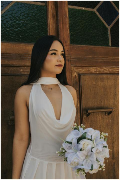 Bride in elegant white dress holding bouquet, posi