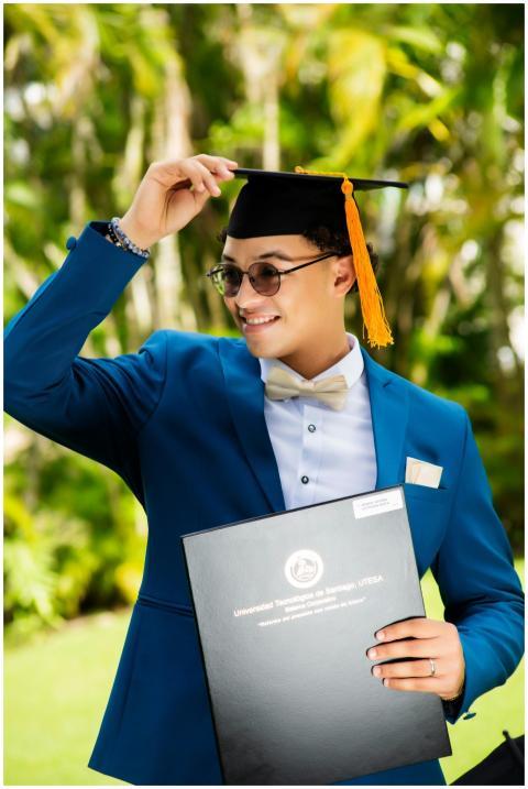 A happy young graduate in a blue suit celebrates o