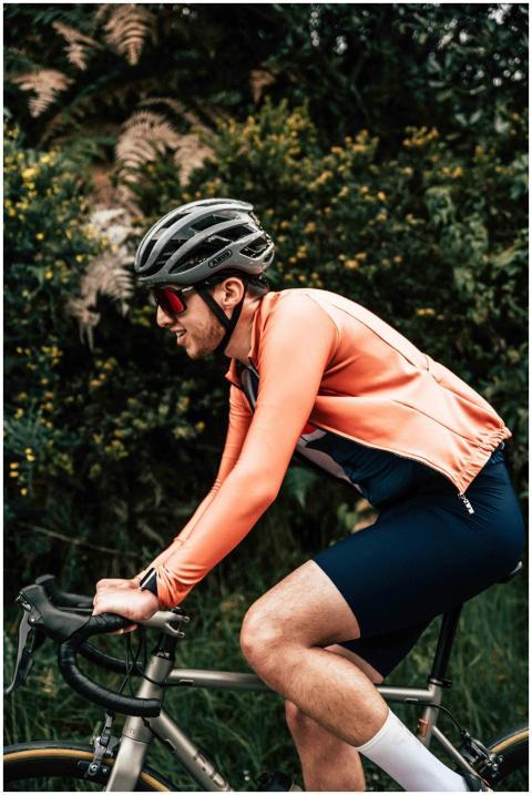 Cyclist in orange jacket and helmet biking through