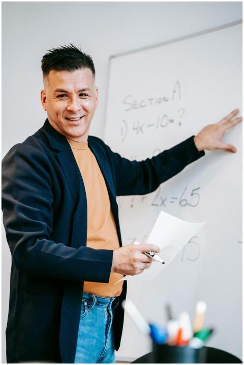 Friendly teacher explains equations on a whiteboar