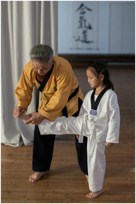 Instructor assists young girl in martial arts trai