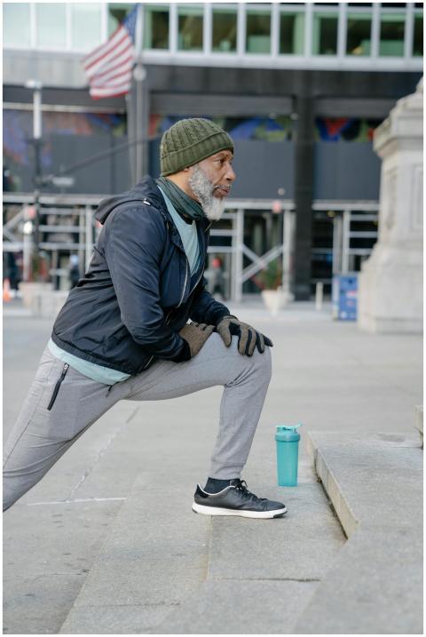 Elderly man in sportswear stretching outdoors on c