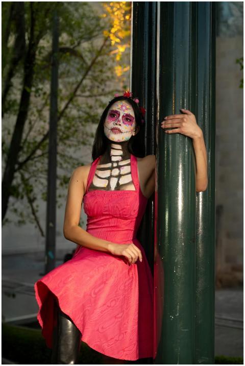 Woman in pink dress with Day of the Dead makeup le