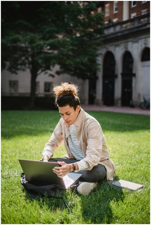 A young man concentrating on his laptop while sitt