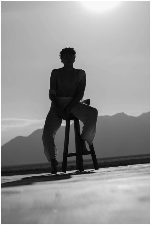 Black and white silhouette of a man sitting on a s