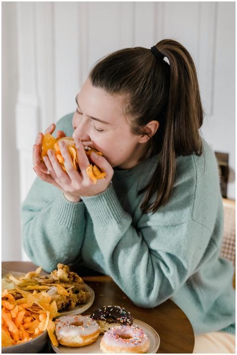 Hungry female in casual clothes eating crispy chip