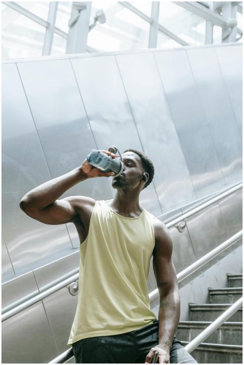 Fit young man hydrating with water bottle on city