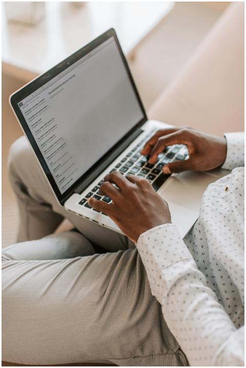 An adult typing on a laptop in a cozy home environ