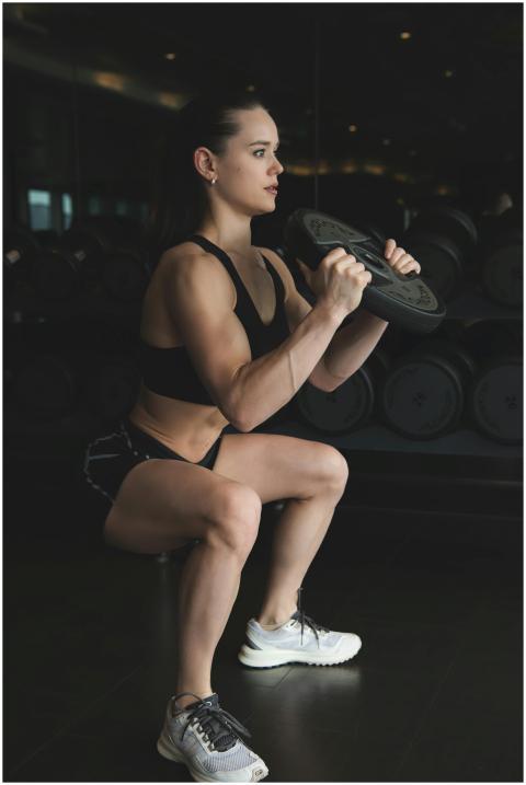 Focused woman doing weighted squats in a gym showc