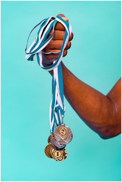 Close-up of a hand holding various medals with blu