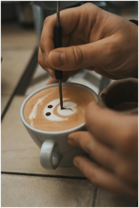 A person skillfully crafting detailed latte art in